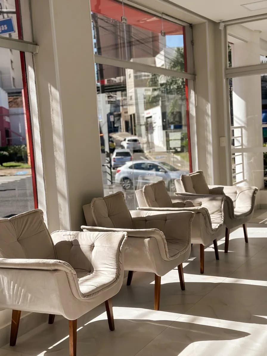 Sala de espera da Clínica Oral Sorriso, com poltronas junto à vidraça, em Uberlândia